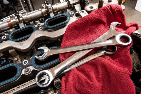 Open End Ratcheting Wrench Set, 8-Piece SAE 12-Point placed on red cloth near engine parts