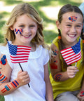 Two girls holding USA flags, wearing 4th Of July Women Outfit Set With 120 PCS USA Flag Temporary Tattoos for a festive vibe.