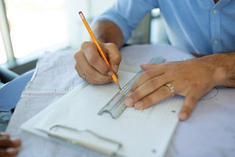 Person using Heavy Hitter Yellow Number Two Pencils Presharpened For Butter Smooth Writing on grid paper with a ruler.
