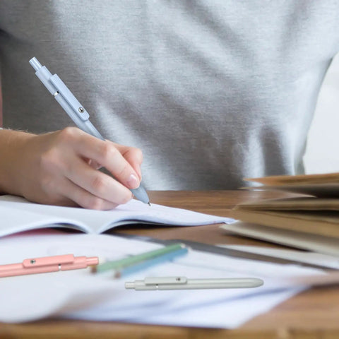 Person writing with Retractable Gel Ink Pens With Refills For Smooth Quick Dry Writing Leak Free And Smudge Resistant Office Supplies