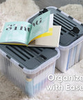 12 Pack Heavy Duty Clear Deep Storage Containers With Secure Hinged Lids 27.5 Quart Snap Close Bins on carpet with opened book.