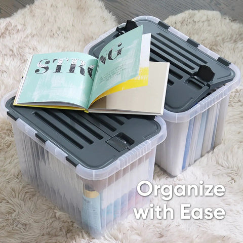 12 Pack Heavy Duty Clear Deep Storage Containers With Secure Hinged Lids 27.5 Quart Snap Close Bins on carpet with opened book.