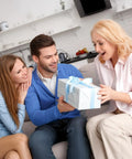 Family enjoys gift giving moment in cozy kitchen, excited expressions, nicely wrapped present with blue ribbon.