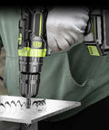 Cordless power drill with tungsten carbide masonry bit drilling into a metal sheet; green and black tool with battery pack.