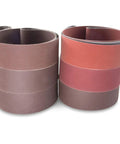 Knife Makers Sanding Belts 2x42 Inch Fine Grit Kit 6 Pack P180 P220 P320 P400 P600 P800 For Knife Making Sharpening And Metal Working Pro Grade Aluminum Oxide Belts displayed in stacked rolls.
