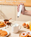 White handheld milk frother in use over a mug for lattes with breakfast items around, part of Two Pack Handheld Milk Frother With Stand For Lattes Cappuccinos Matcha And Hot Chocolate Go To Valentines Day Gift For Him And Her Black And White.