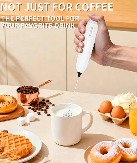 White handheld milk frother in use over a mug for lattes with breakfast items around, part of Two Pack Handheld Milk Frother With Stand For Lattes Cappuccinos Matcha And Hot Chocolate Go To Valentines Day Gift For Him And Her Black And White.