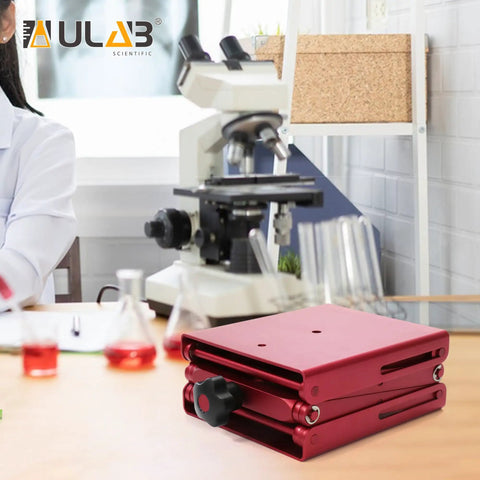 Heavy Duty Aluminum Lab Jack Platform Lift Table With 4.8 By 5.5 Inch Platform Adjustable Height From 2.3 To 9.5 Inches Corrosion Resistant Reusable Precision Lift For Science Workbenches And Bench Top Tasks next to a microscope in a lab setting.