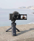 Wireless Bluetooth Shooting Grip And Tripod For Still Photos And Video Perfect For Vlogging Cable Free Remote Commander Dust And Moisture Resistant Flexible Tilt Quick Direction Changes GP VPT2BT displayed on a ledge by the sea with a camera mounted