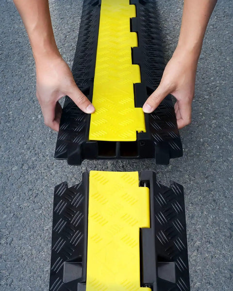 Hands assembling Two Channel Cable Protector Ramp, 3-pack, heavy-duty, yellow and black design for 11000 lbs axle load.