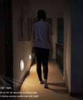 Person walking down a hallway illuminated by 6 Inch 120 Volt LED Closet Light With PIR Motion Sensor Ceiling Disc Light 15W 1100 Lumens CRI Over 80 Daylight White 5000K Wet Location ETL