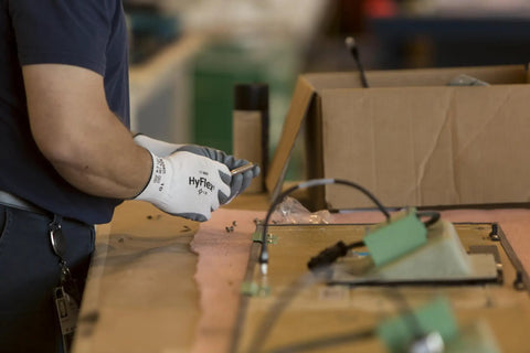 Worker wearing HyFlex 11-800 nylon work glove with gray foam nitrile coating, size 9 large, handling tools in an auto shop.