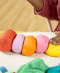 Game Changing Modeling Compound Haul With 65 Mini Cans Serving Up Sixty Varieties Including Rainbow Classics Plus Sparkle Confetti and Color Burst Vibes Ideal for Back to School Supply Lists and Preschool Projects for Kids Two Plus showing bright colored clay lumps arranged on a surface.