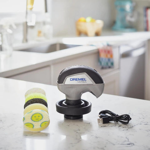 Versa Power Scrubber Grout Brush And Shower Cleaning Tool displayed on a kitchen countertop with pads and USB charger.