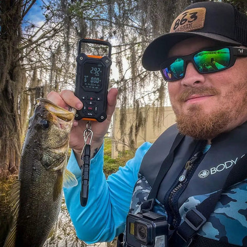 Man outdoors using Tournament-Ready Digital Fishing Scale With Auto Rank And 8 Storage Slots, Lip Gripper, Large Backlit LCD Display.