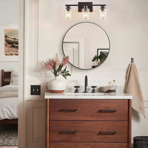 Sleek Matte Black 3 Light Vanity Light With Clear Glass Shades For Bathroom above a modern wood vanity and round mirror