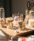 Glass jars with cork lids and Heavy Duty 2 Inch Screw Eyes Set In 304 Stainless Steel on a wooden tray.