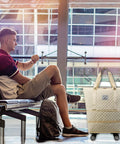 Front view of a white quilted rolling duffle bag with wheels and carrying handles, carry-on size (Amazon).