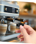 Hand holding Espresso Steam Wand Heat Insulation Sleeve Anti Burn Rubber Wrap For Coffee Machines next to espresso machine.