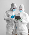 Two individuals in white hooded coveralls with boots, examining a tablet. Product: White Hooded Coveralls With Boots Pack Of 5 60 GSM SMS