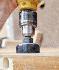 Close-up of a 11 Piece Hole Saw Kit With Mandrel And Hex Key in action on wood, creating a circular cut with sawdust.