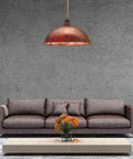 Living room with large brown sofa, industrial red pendant light, and low wooden table with orange flowers.