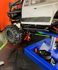 Four red metal 3/6-ton RC jack stands for 1/10 scale crawlers, shown lifting a D90 Axial Wraith SCX10.