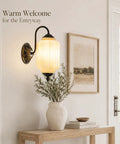 RONGHUAFUGUI Vintage Modern Wall Sconce with Amber Glass on an entryway wall beside a vase with greenery.
