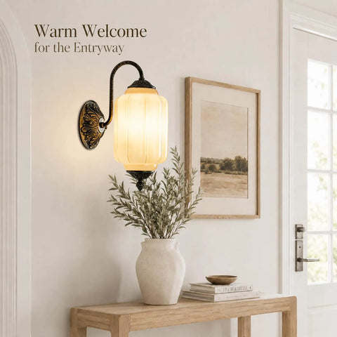 RONGHUAFUGUI Vintage Modern Wall Sconce with Amber Glass on an entryway wall beside a vase with greenery.