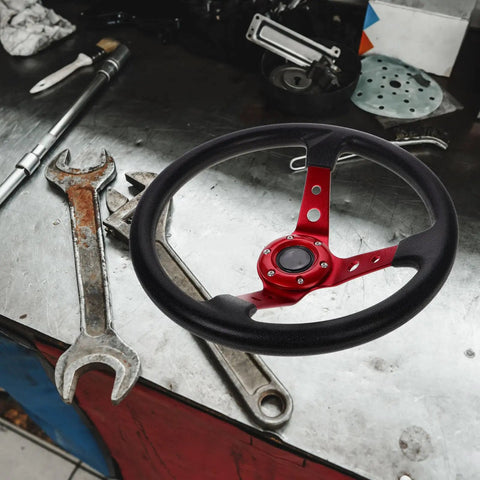 Universal 14 Inch Red PU Racing Steering Wheel With Horn Button on a workshop table with tools.