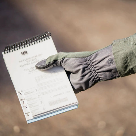 Nomex Flight Gloves 2.0 Sage Medium holding a notebook, showing upgraded fit and supple dexterity with leather reinforcement.
