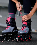 Macroblade 90 W Inline Skates for Women in Neutral Grey and Paradise Pink being laced up, featuring 90mm wheels and aluminum frame.