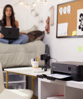 All In One Wireless Inkjet Printer Print Copy Scan With Alexa 1.44 Inch Oled Display Front Rear Paper Trays Plug And Play Setup Slick Workflow Black Home Office Prints on a desk with paper printing.