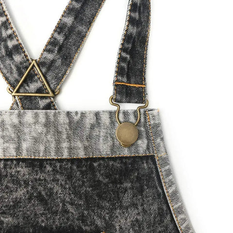 Close-up of Denim Hair Stylist Tool Apron with cross back straps, black denim fabric and metal buckle detail.