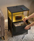 LED Nightstand With Charging Station, USB Ports And Outlets, Dope RGB Color Changing LED Night Light, Built In Storage Drawers, Modern Black Finish in use next to sofa.