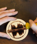 Person engraving a design onto a Sweet Unfinished Wood Circles For No Sweat Diy Crafting With Pack Of Thirty Six Three Inch Wooden Rounds.