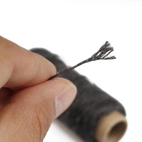 Close-up of hand holding black waxed leather thread spool, part of Waxed Leather Sewing Thread Kit With 55 Yard Spools And Pro Grade Needles, DIY Weave Repair For Upholstery, Car Interiors, Bags, Leather Craft, Canvas And Home Projects, 8Pcs Black.