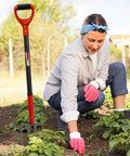 Woman gardening beside a Heavy Duty 4-Tine Garden Spading Fork With 43 Inch Fiberglass Handle, 7x3.5 Inch Head, 1050 Manganese Steel