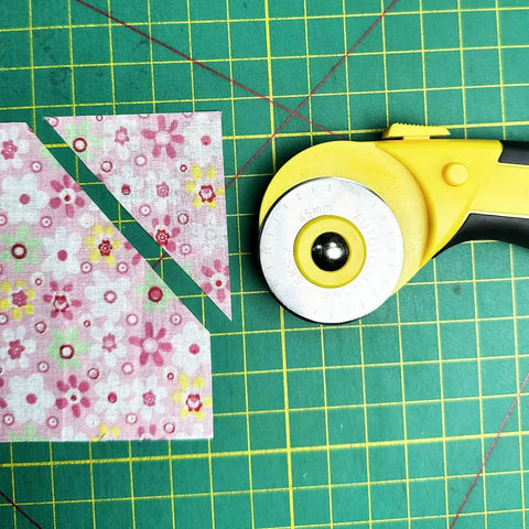 45Mm Rotary Cutter Kit with 9 Extra Blades for Fabric Quilting and Crafting next to cut floral fabric on green grid mat