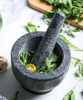 Granite Mortar And Pestle Set For Grinding Spices And Herbs Like A Boss, Natural Non Porous Stone filled with herbs on marble.
