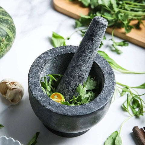 Granite Mortar And Pestle Set For Grinding Spices And Herbs Like A Boss, Natural Non Porous Stone filled with herbs on marble.