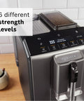 Fully Automatic Espresso Machine With Milk Frother System And Touch Control Panel Plus Cup Warmer For One Touch Latte And Cappuccino Maker In Sleek Dark Silver showing touchscreen with beverage selection.