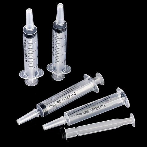 Large Plastic Syringe 4 Pack For Measuring And Dispensing Fluids Sterile Wrapped 20 Ml Syringe Set lying on black background
