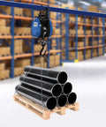 Heavy Duty Electric Chain Hoist, 1100 Lb Capacity With 1800 Watt Motor lifting black pipes on a wooden pallet in a warehouse.