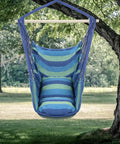 Heavy Duty Hammock Chair Hanging Rope Swing With Steel Spreader Bar For Indoor And Outdoor Relaxation Macrame Seat With Two Cushions Supports Up To 550 Lbs Blue Green Stripe in a natural outdoor setting