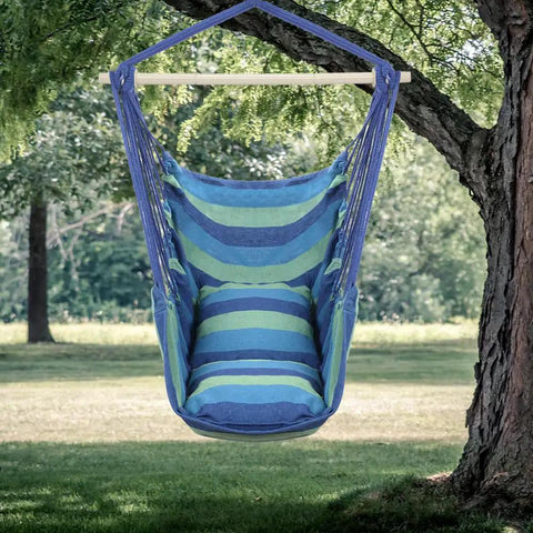 Heavy Duty Hammock Chair Hanging Rope Swing With Steel Spreader Bar For Indoor And Outdoor Relaxation Macrame Seat With Two Cushions Supports Up To 550 Lbs Blue Green Stripe in a natural outdoor setting