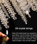 Close-up of K9 crystal raindrop pendants on gold finish tree branch chandelier with flame test for authenticity.