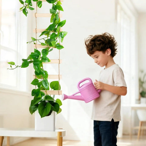 Child watering plant on an extra tall six foot wooden ladder plant trellis for indoor and outdoor garden support easy to install climbing vine trellis for ivy pothos monstera philodendron and other potted plants, showing natural wood sections and lush green vines climbing upward.
