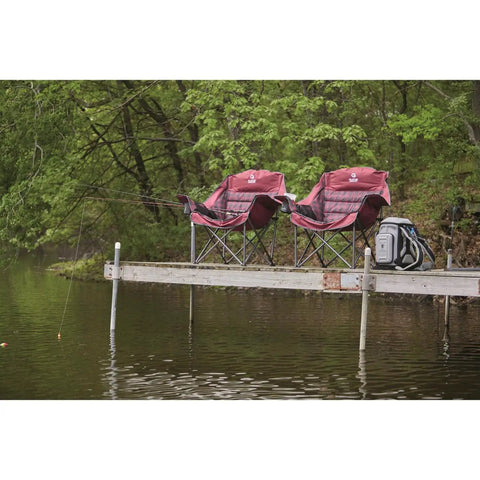 Two red camping chairs on a dock by a lake with fishing rods, showcasing outdoor use of Oversized Extra Large Padded Camping Chair Portable Folding Lounge With Cup Holder Green For Outdoor Camping Beach And Travel Heavy Duty 400 Pound Capacity Ultra Cozy All Day Chill For Adults Men And Women.
