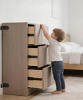 Child near dresser secured with Anti Tip Furniture Anchor Kit For Baby Proofing Dresser And Bookcase, Easy Wall Mount, Black.